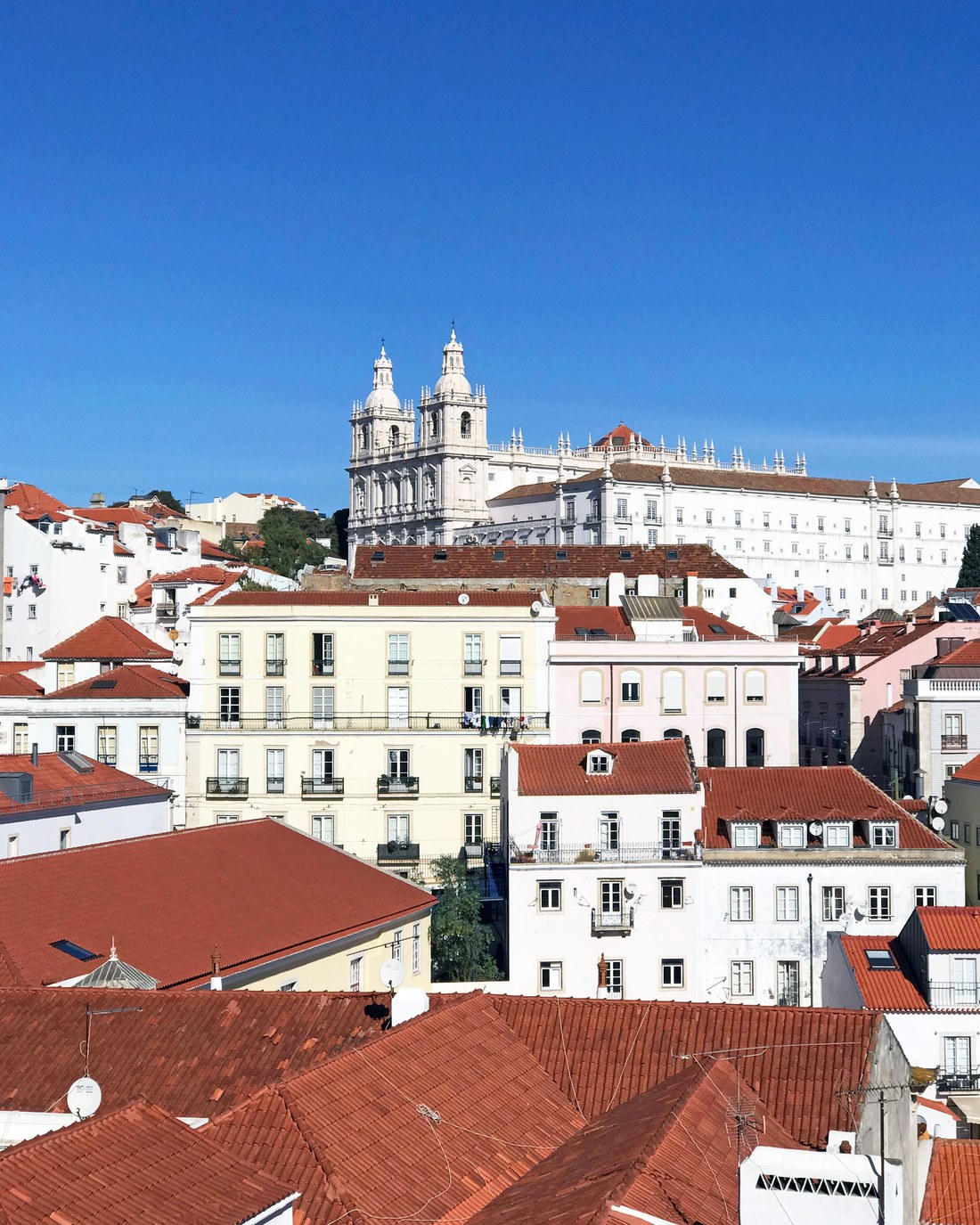Terracotta rooftops in Lisbon under a clear blue sky